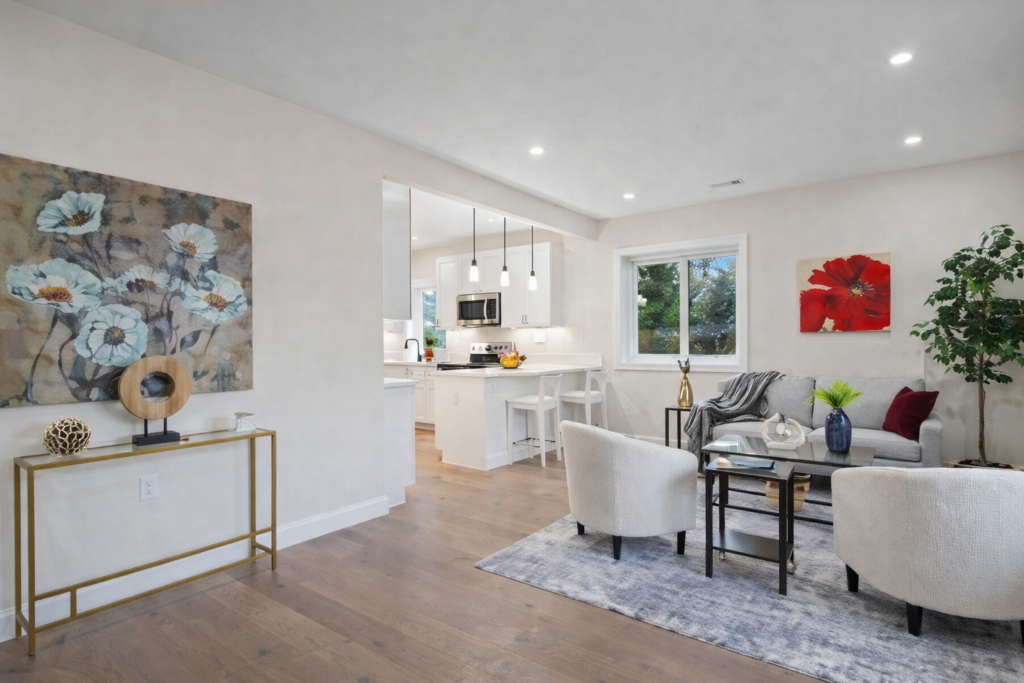 Modern open concept living room and kitchen with neutral furniture, gray rug, hardwood floors, and bright natural lighting