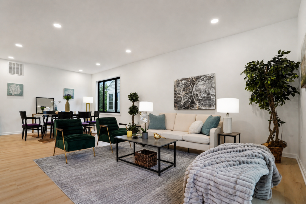 modern open living room with beige sofa, green chairs, coffee table, and dining area in background