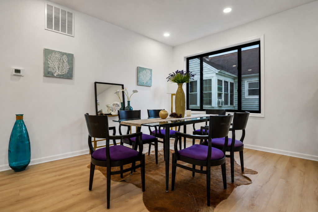 modern dining room with black chairs, purple cushions, glass table, and large window