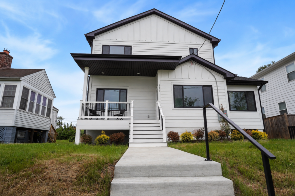 modern white two story house with front porch steps and landscaped yard in suburban neighborhood