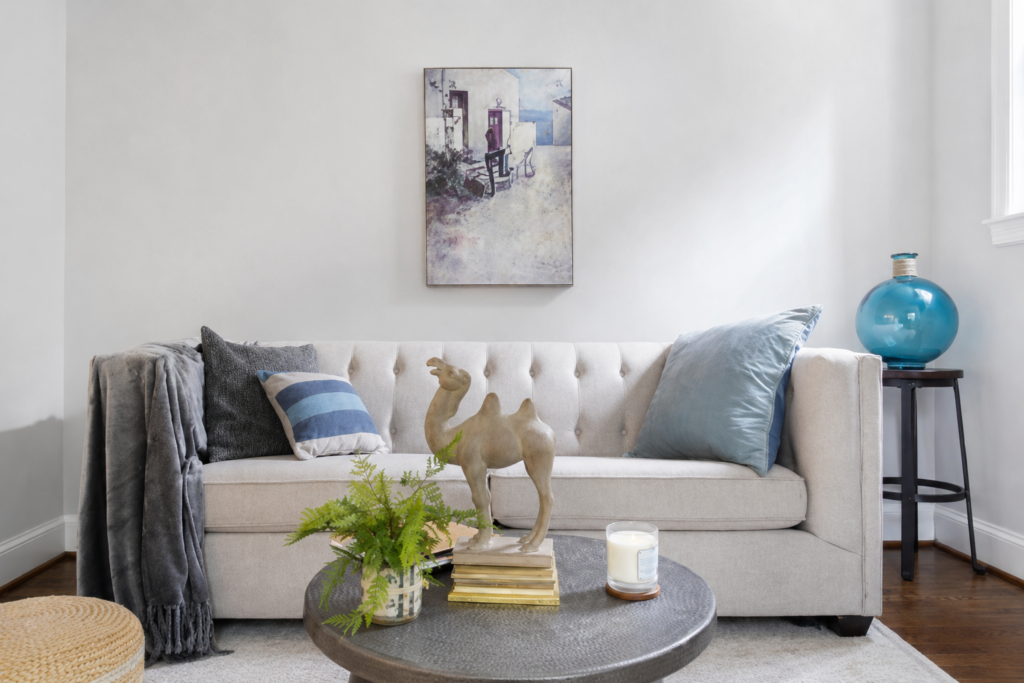 Minimalist living room with beige tufted sofa, neutral decor, round coffee table, and soft natural lighting