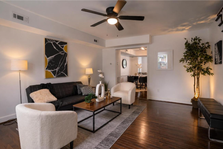Professionally staged living room in Washington DC with dark sofa white accent chairs and gold artwork