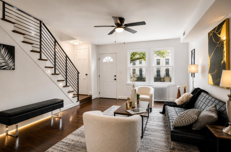 Staged Living Room and Entryway Washington DC Harvard Home Services Professionally staged living room and staircase entryway in Washington DC townhouse with black sofa and gold artwork